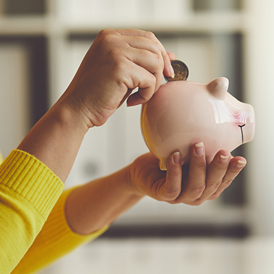 Person putting coin into piggy bank