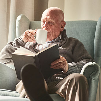 Older man drinking coffee and reading a book